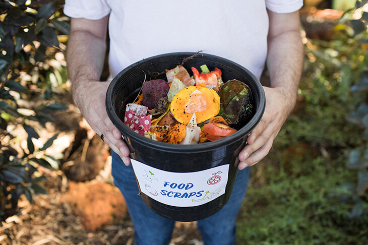 Man holding a container of compostable food scraps