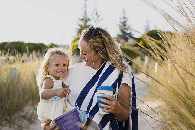 Mother holding her daughter at the beach