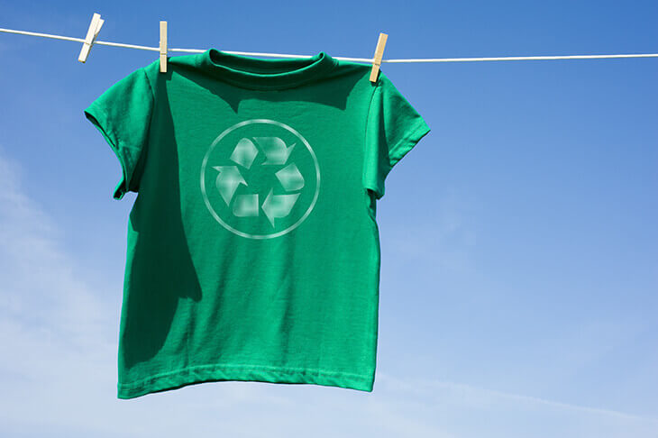 green t-shirt with printed recycle symbol hanging on a washing line