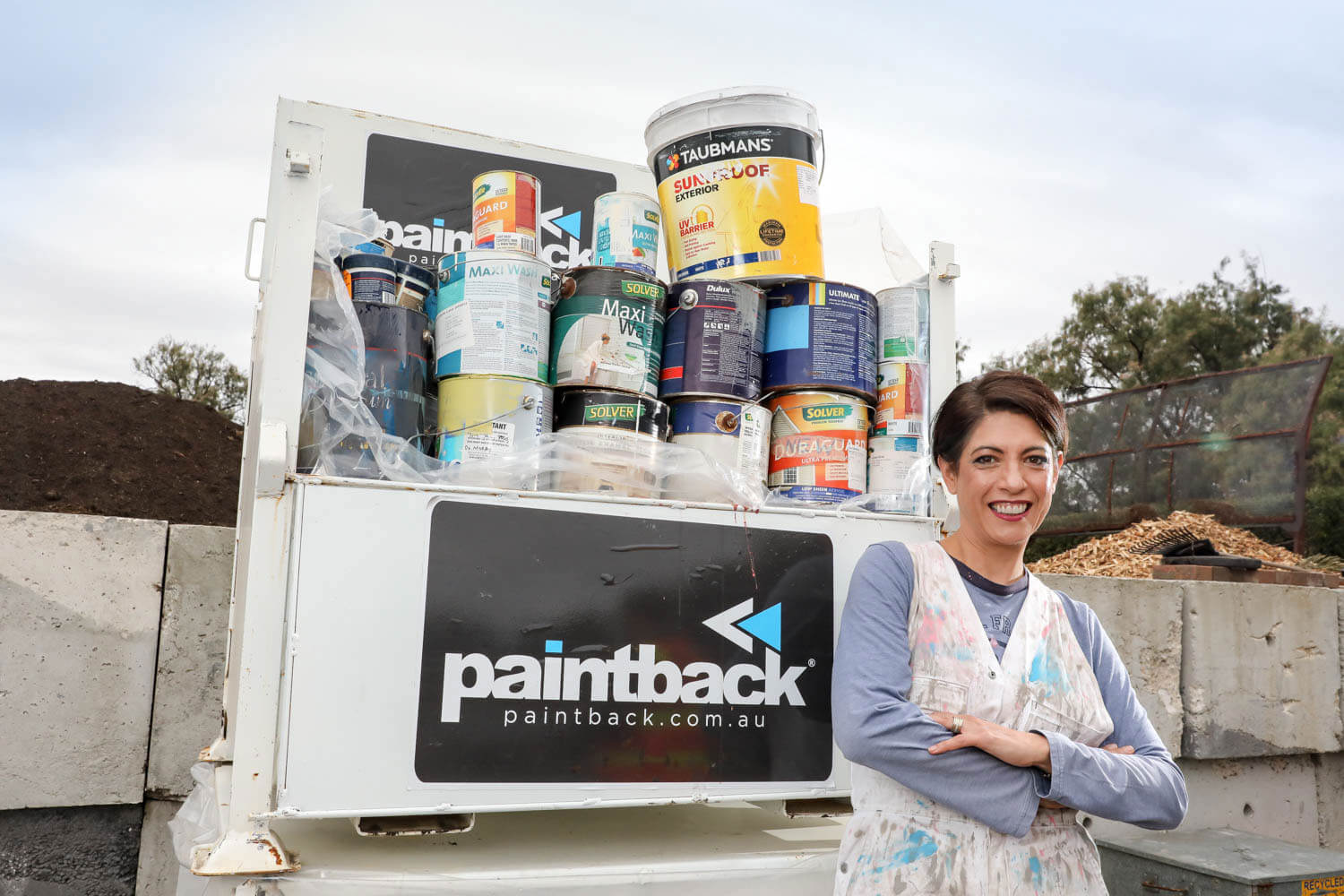 Lady in front of a ute filled with old paint tins