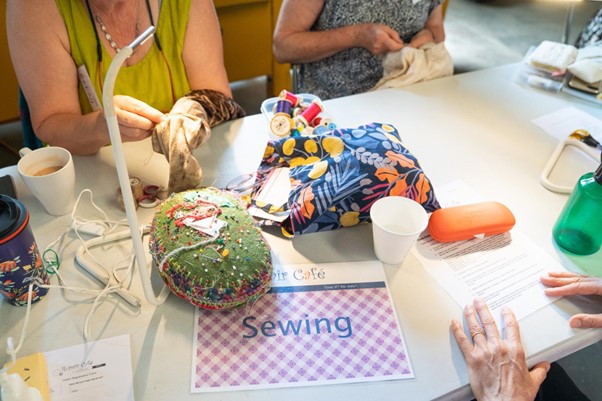 A closeup of people sitting at a table with sewing items