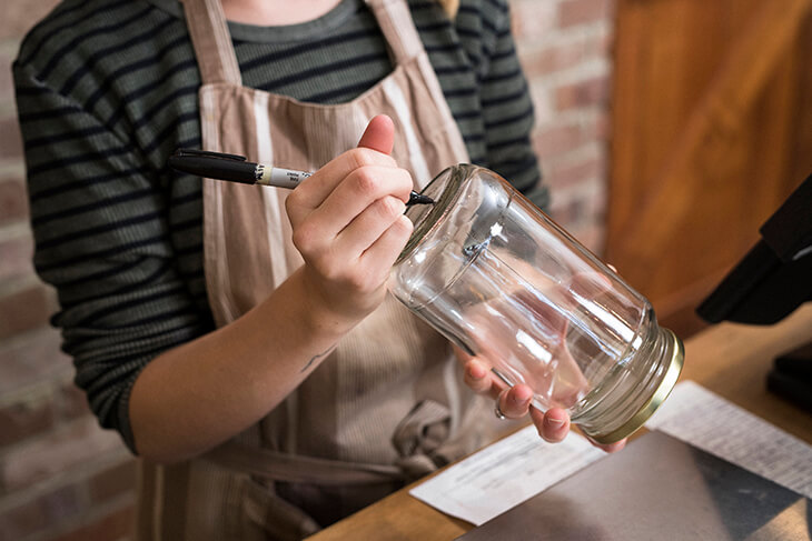 Shop assistant writing on a glass jar