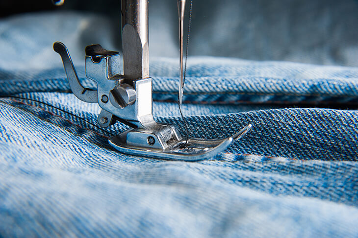 close up of a sewing machine sewing denim