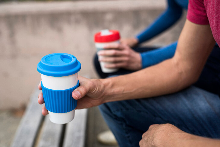 close up of hands holding reusable coffee cups