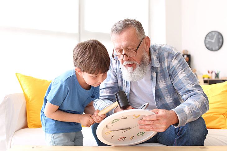 Grandfather teaching young boy how to fix a clock