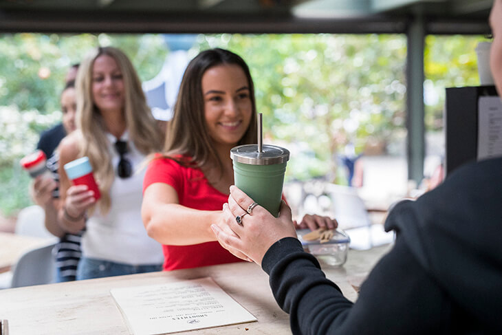 customer recieving a drink in a reusable container