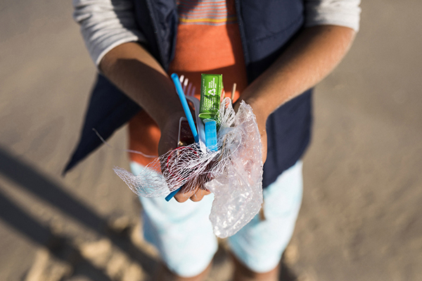 close up of hands holding a bunch of rubbish collected at the beach