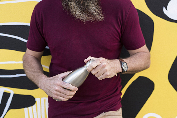 mid-shot of a man holding a reusable drink container