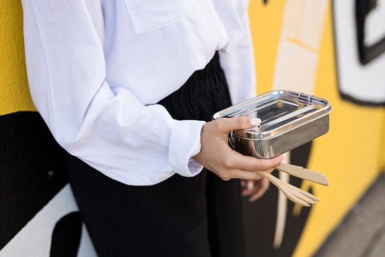 Closeup of lady holding a reusable metal lunch container