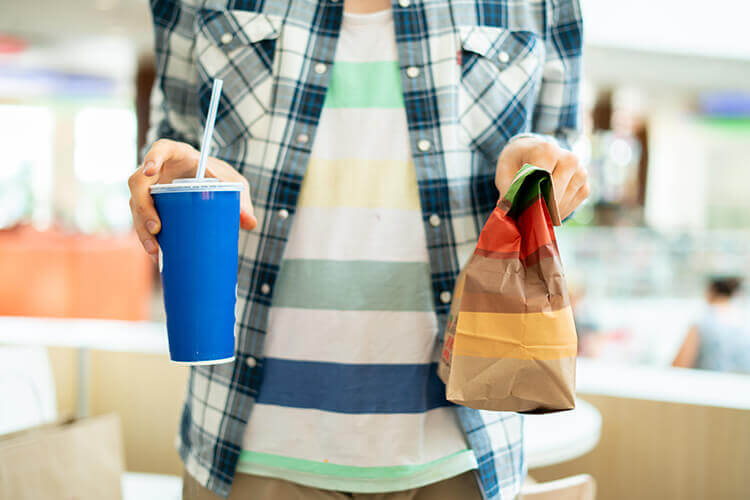 Close up man holding a takeaway cup and takeaway bag of food