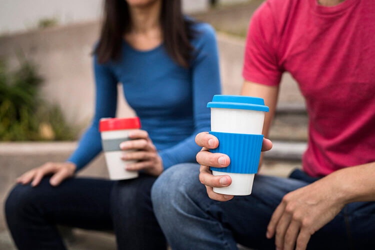 Friends enjoying a coffee in their reusable coffe cups