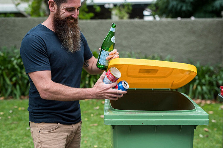 Man placing recyclables into a yellow-topped bin