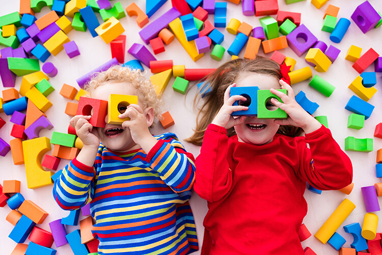 two children surrounded by colourful toy blocks