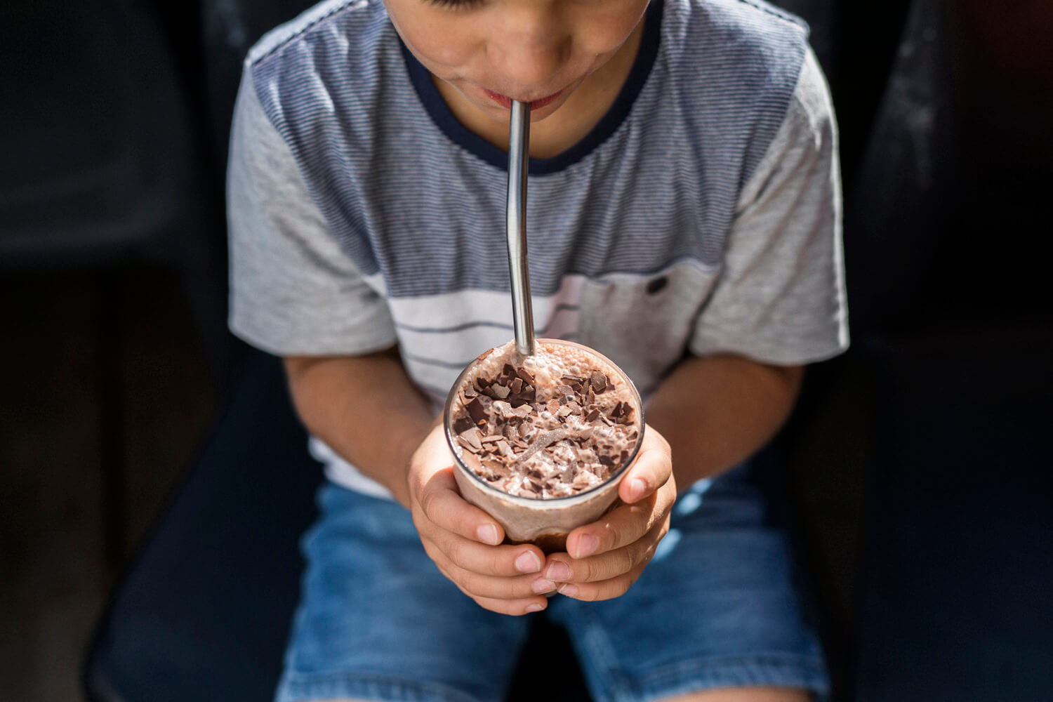 Boy sipping a milkshake through a metal straw