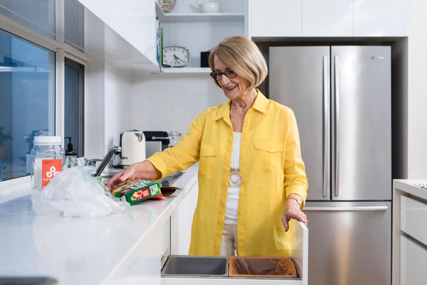 Lady in the kitchen about to place packaging in the recycling bin