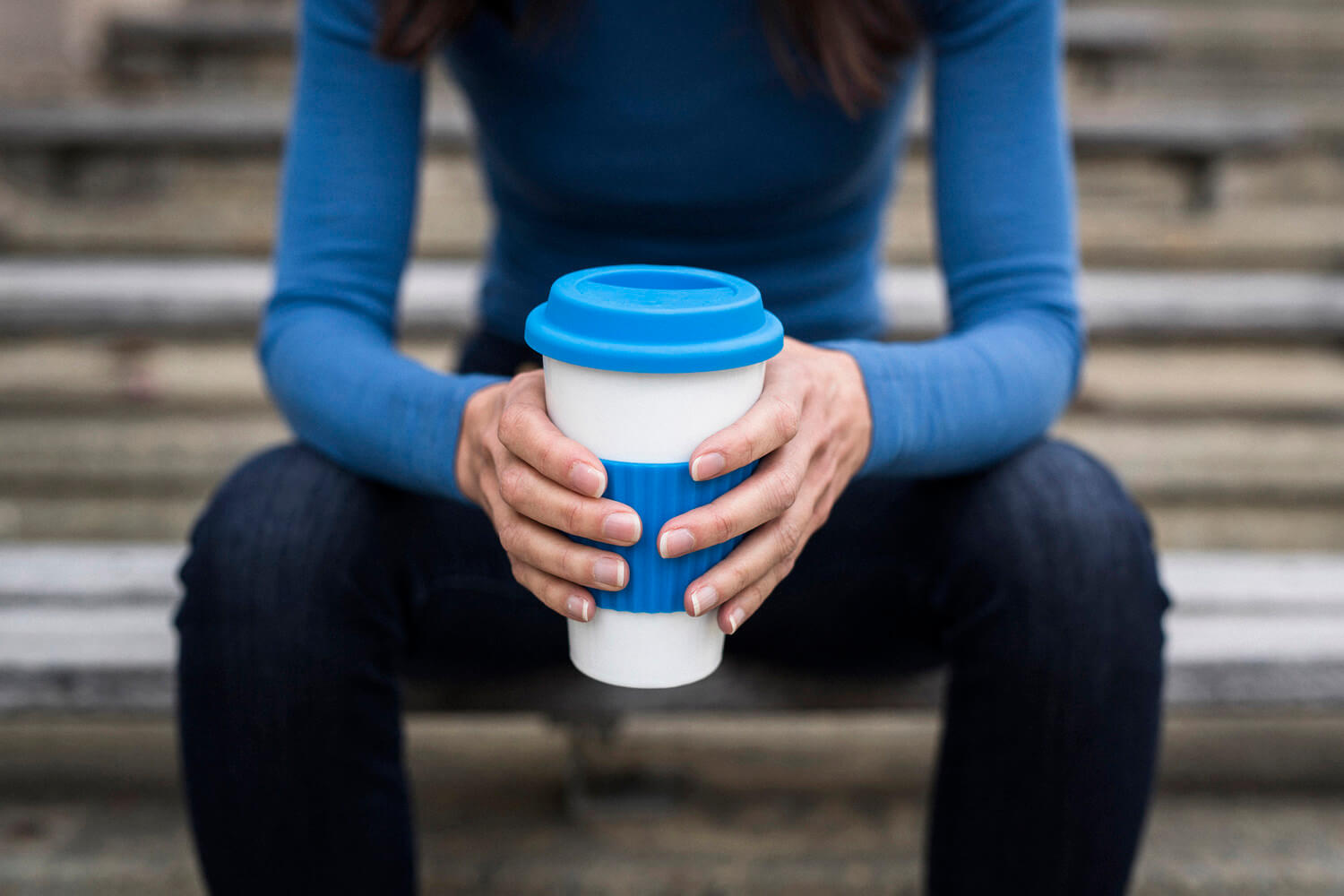 Man sitting and holding a reusable coffee cup